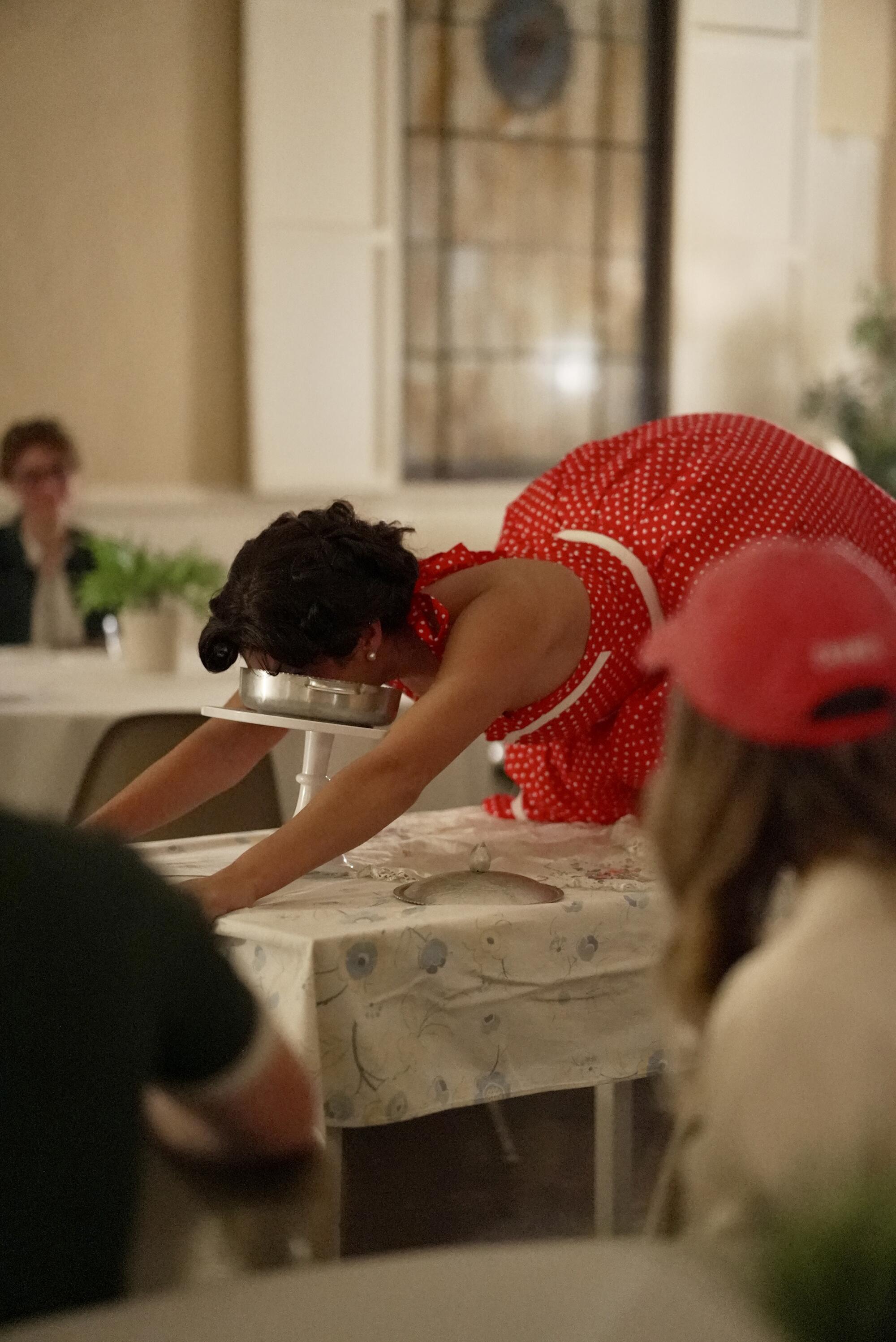 An actor on all fours on a table eating a quiche.