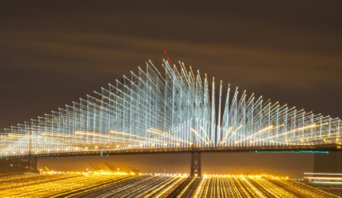 A light show illuminating cables on a suspension bridge shine at night.
