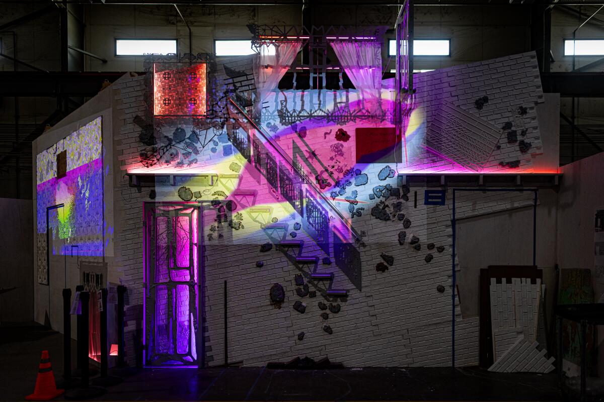 Rainbow lighting lands on the facade of an art piece that looks like a white building.