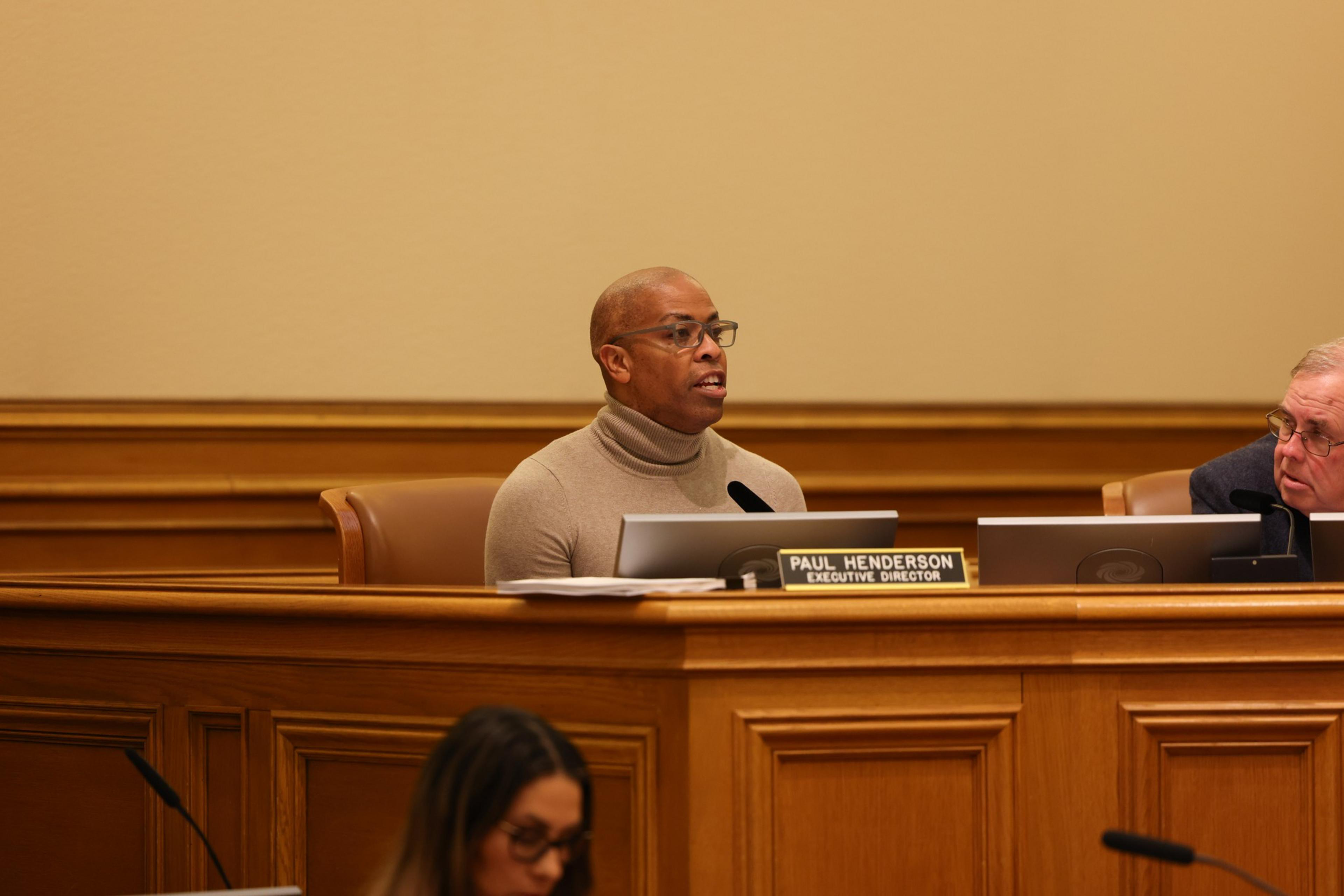 A man sits beside a police commission panel.