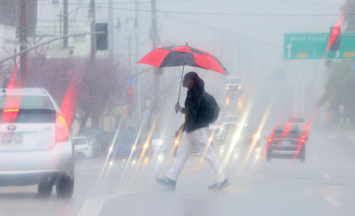 A pedestrian crosses Spring Street in Chinatown during a heavy downpour.