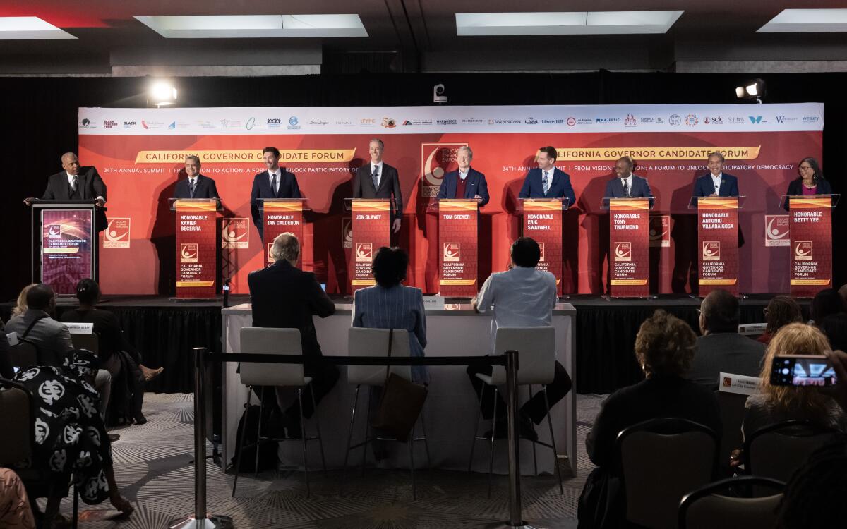 People stand at podiums onstage at a forum for California governor candidates.