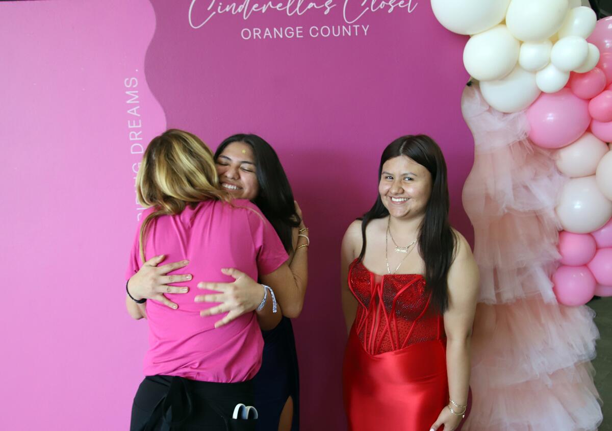 Erin Carlton, left, the founder of Cinderella's Closet hugs Elizabeth Jaime, 18, and Karen Lavios, 17, at Saddleback Church 
