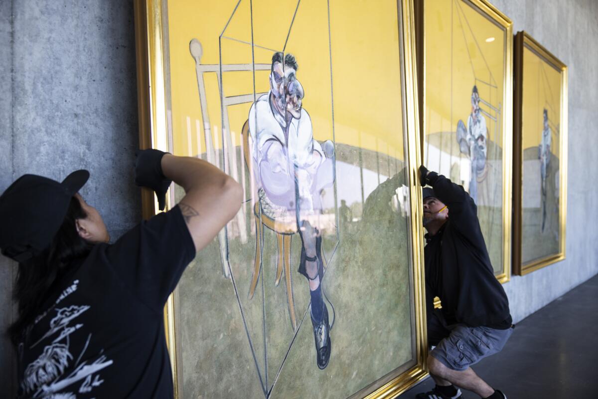 Workers hang a painting.