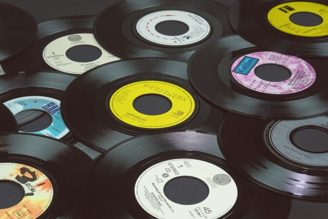 An assortment of black vinyl records without sleeves laid out on a table. 
