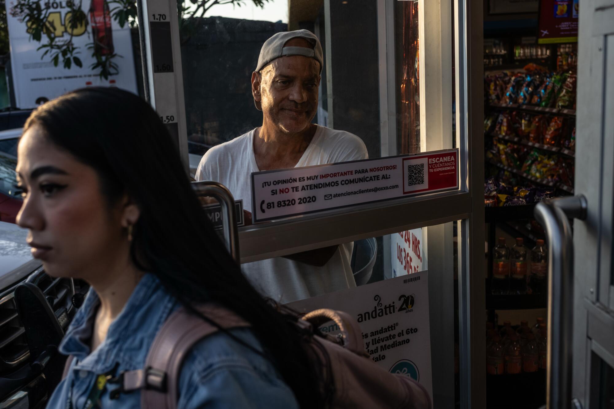 Miguel Martínez Cruz, a Cuban deportee from the United States, opens the door for customers at a convenience store
