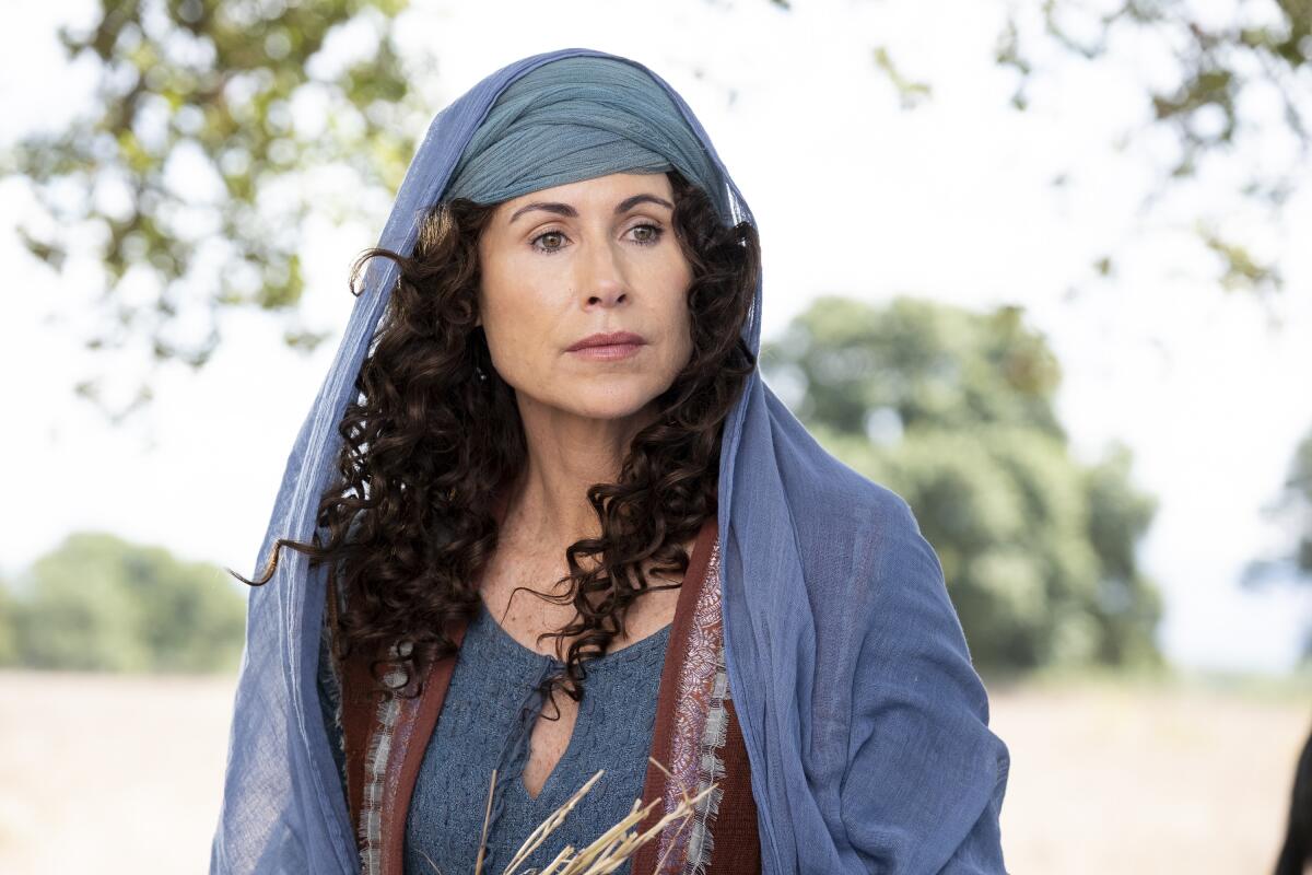 A woman in a blue head covering and blue dress in a field.