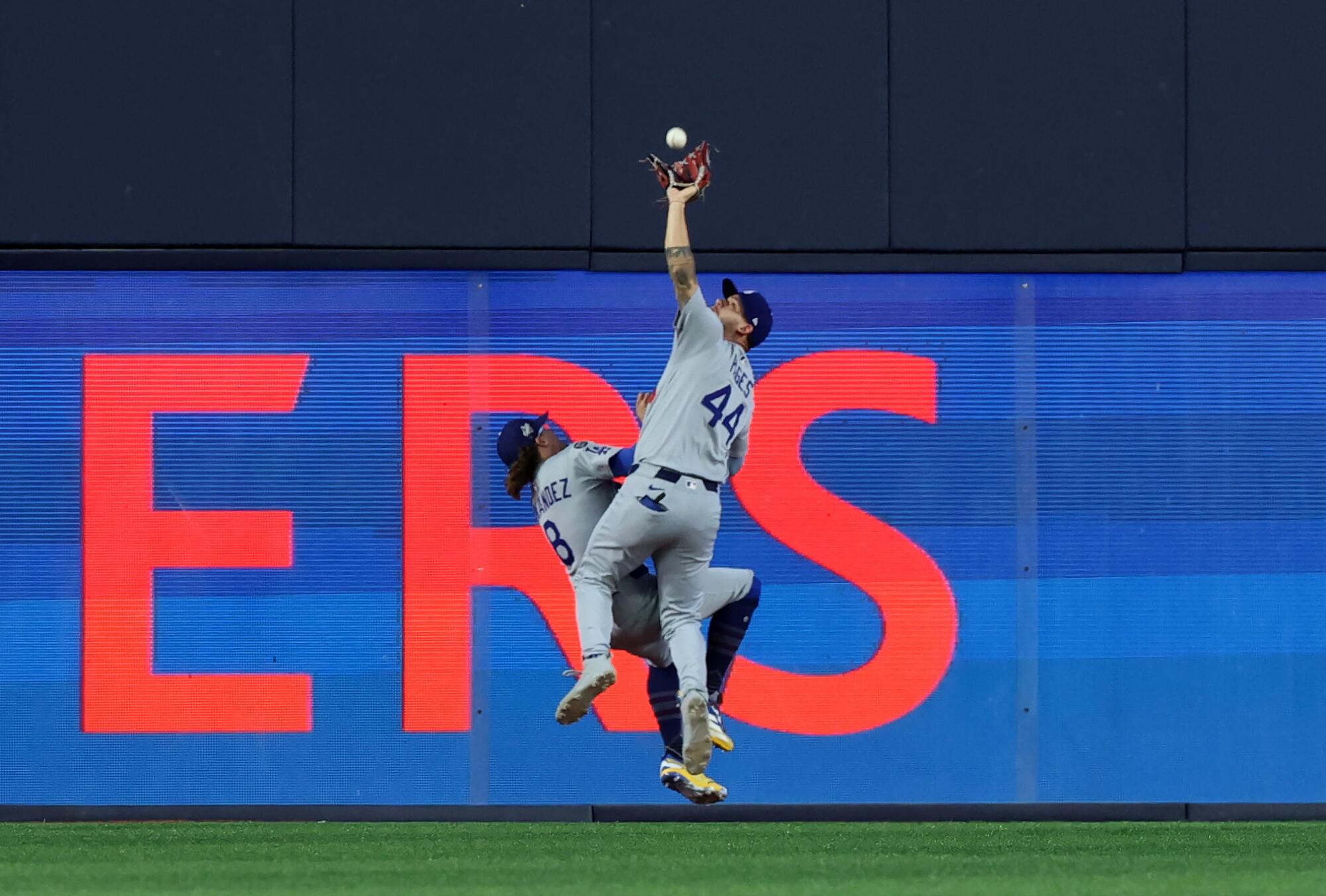 Andy Pages reaches to catch the fly ball hit by Ernie Clement as he collides with Kike Hernandez, left, to end the ninth.