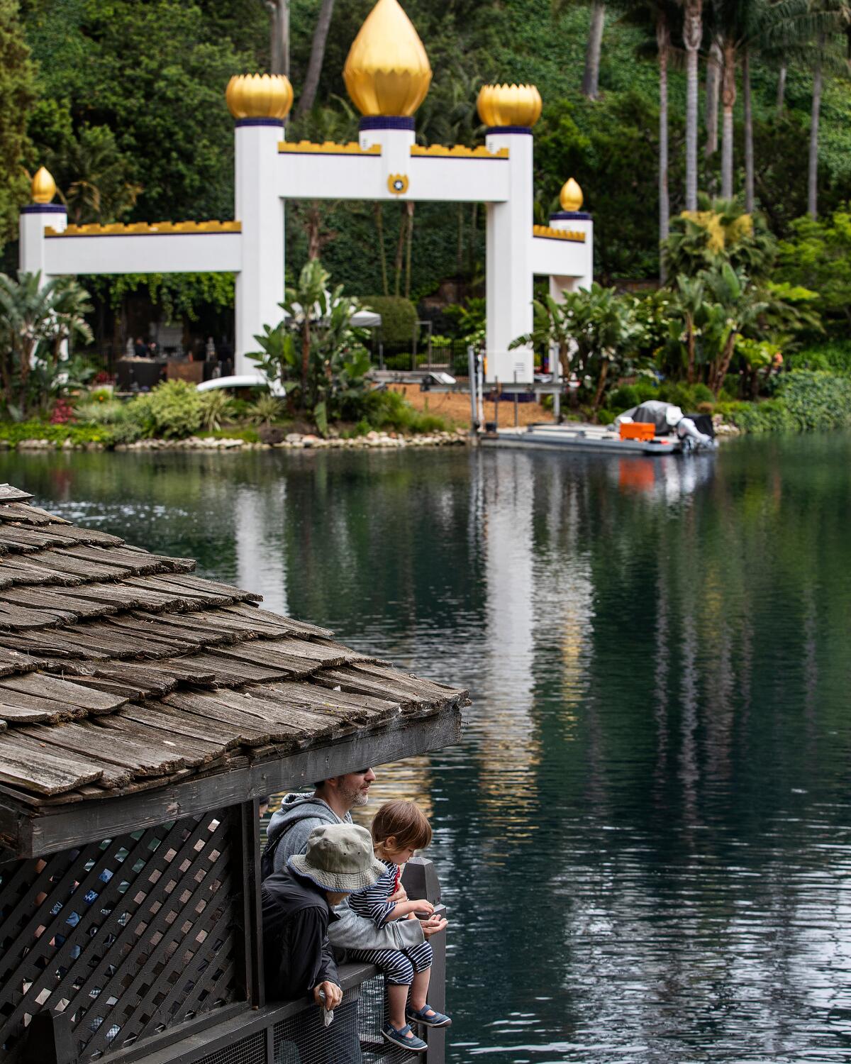  Members of the public watch the Koi fish swim in the lake as the Golden Lotus Archway stands.