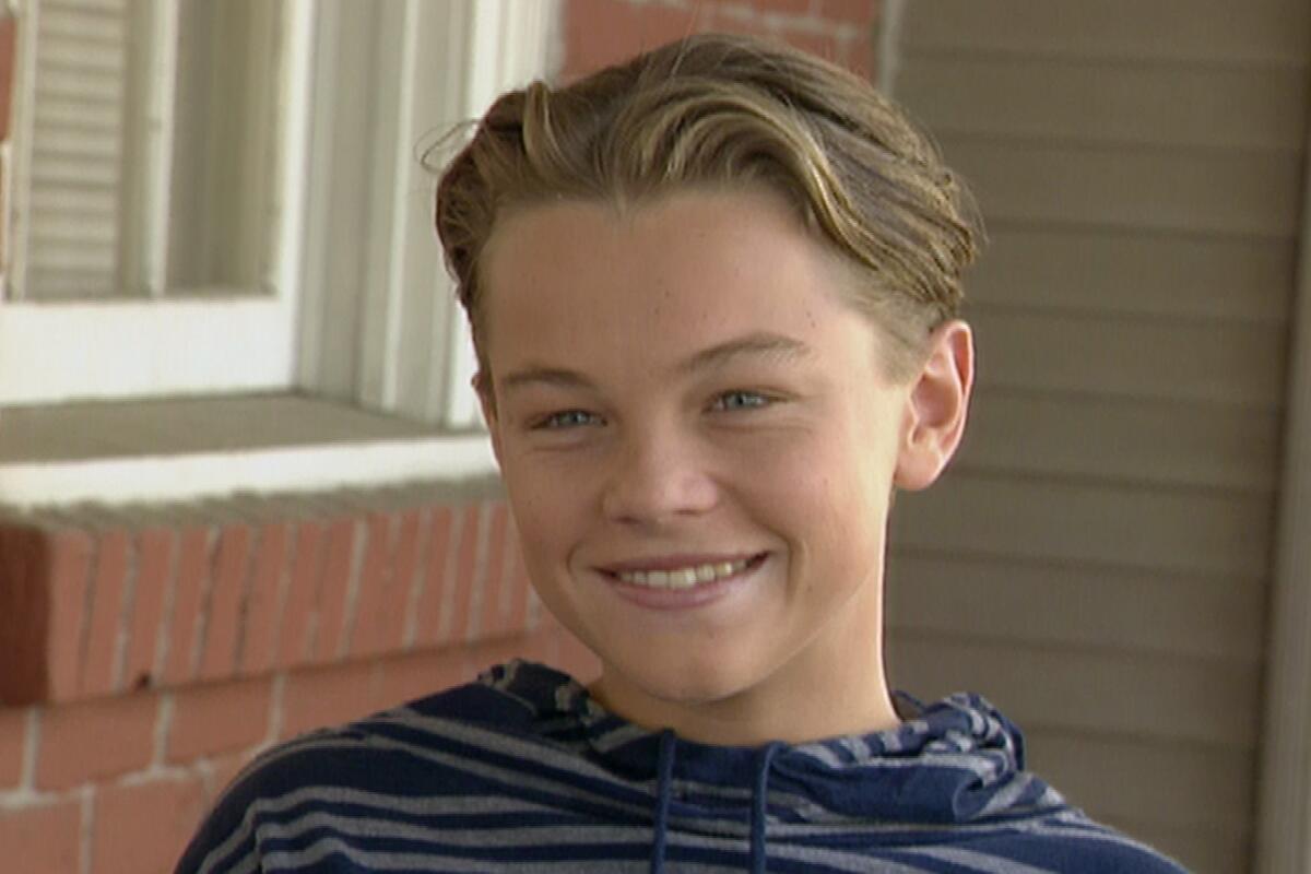A smiling teenage boy in a blue striped hoodie.