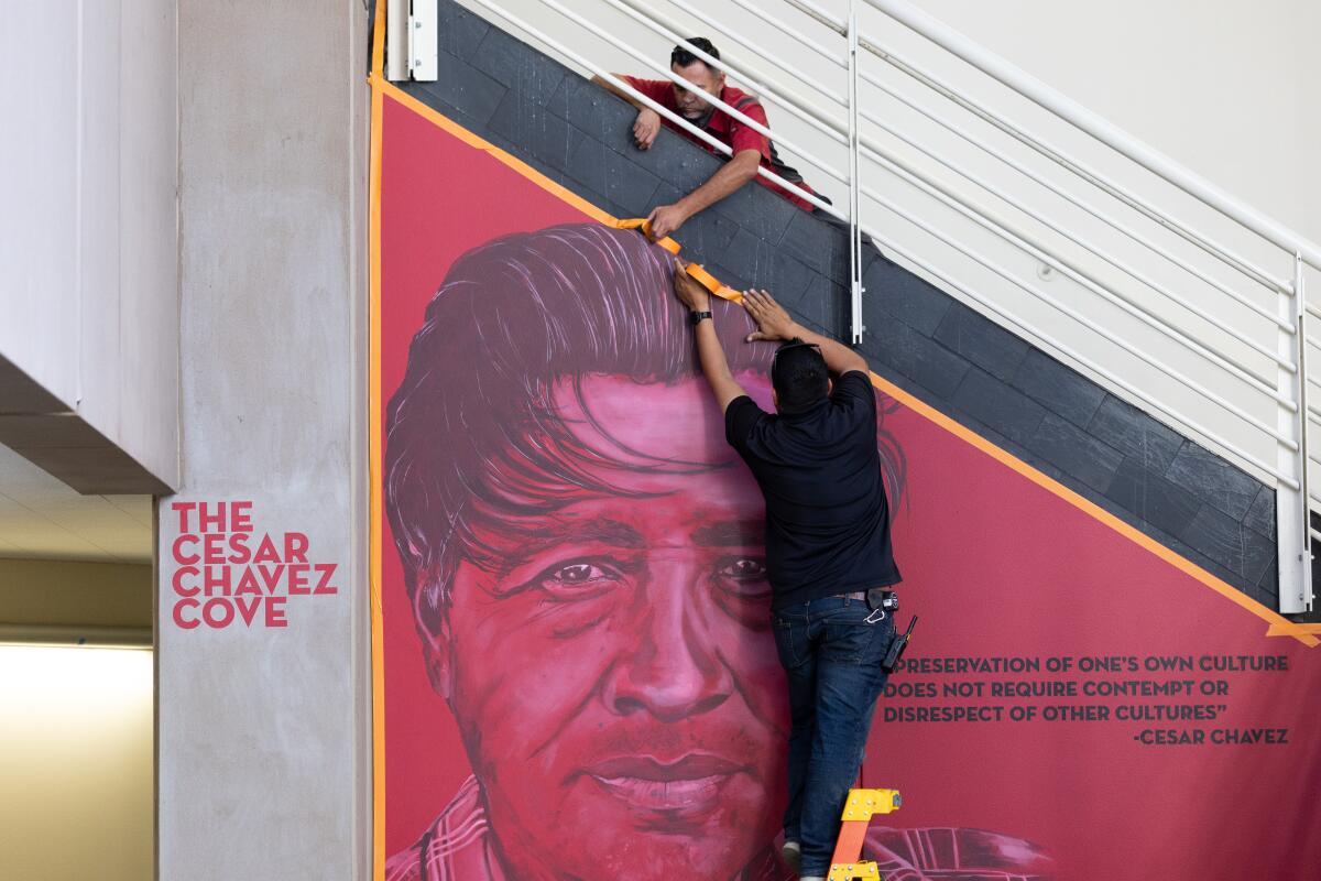 Workers cover up a mural honoring César Chávez.