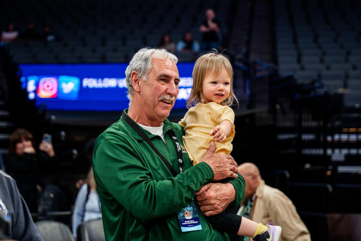 Coach Mike LeDuc of Damien holds up his granddaughter after guiding his team to the state Division I championship.