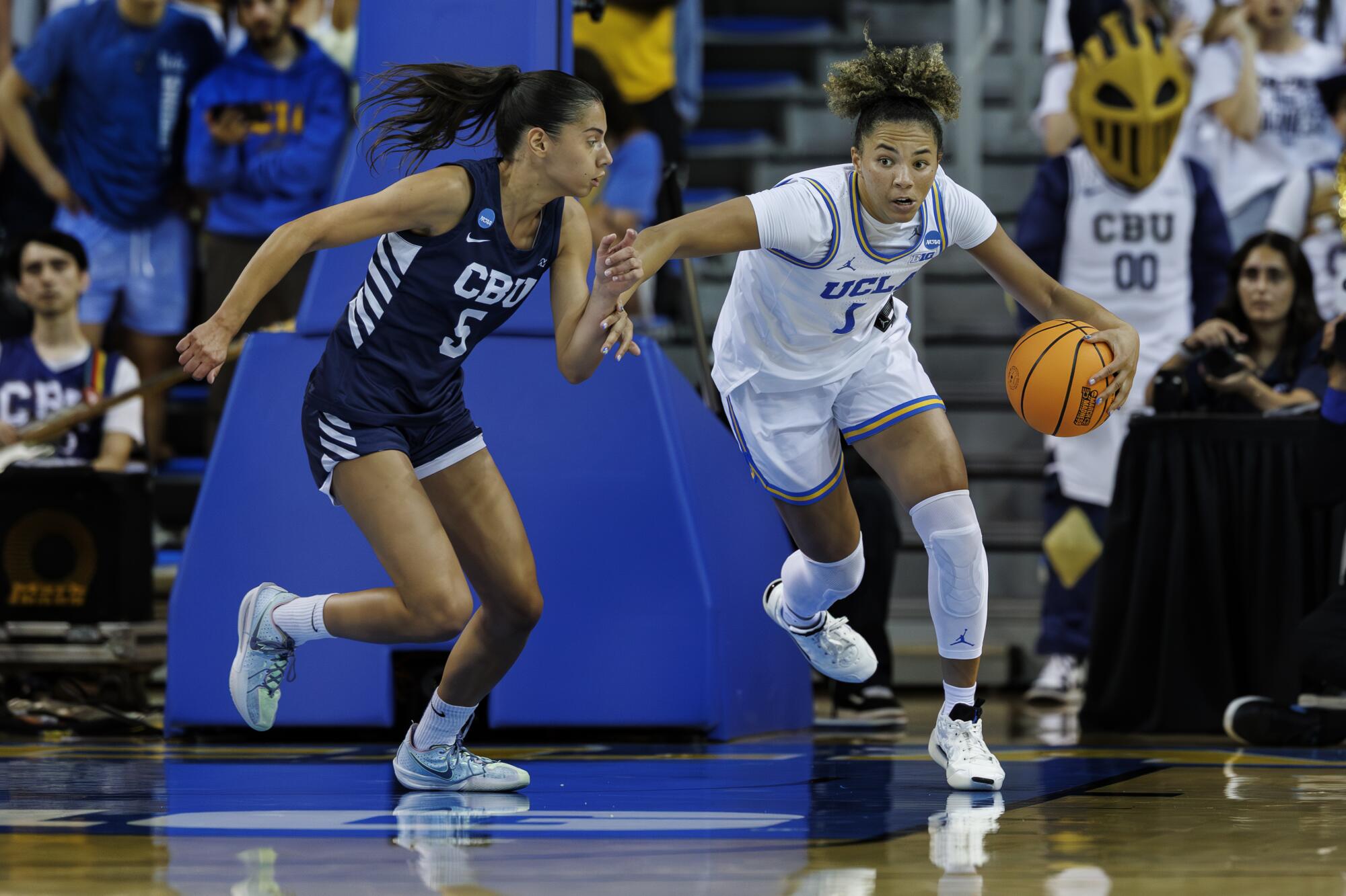 UCLA guard Kiki Rice dribbles up the floor under pressure from California Baptist guard Filipa Barros.