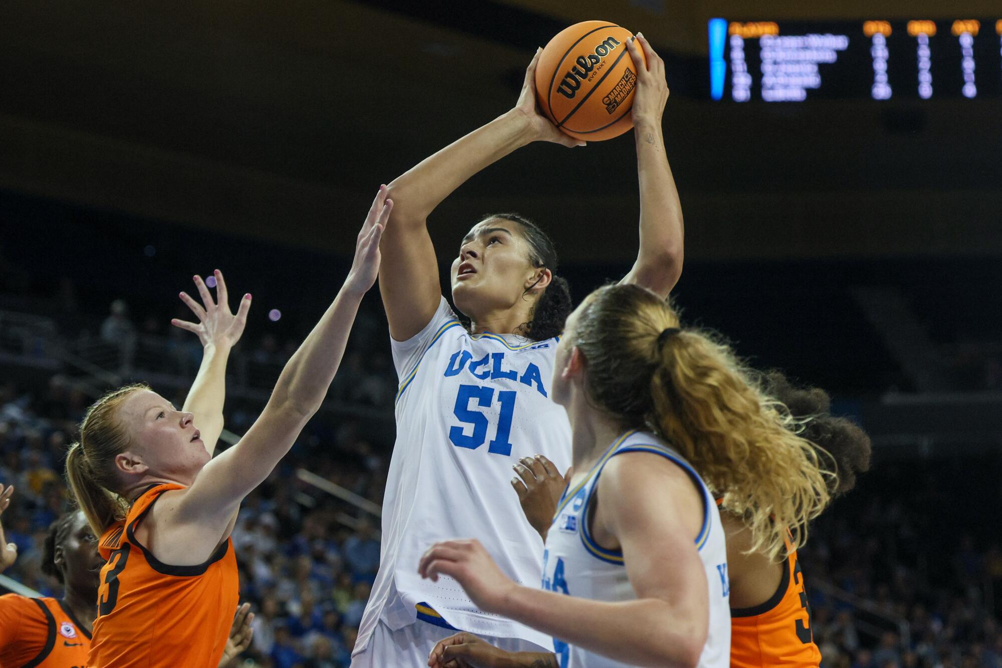 UCLA center Lauren Betts fends off Oklahoma State players while shooting in the paint.