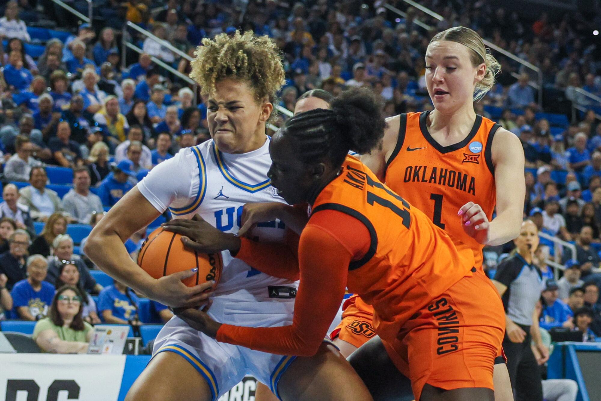 UCLA guard Kiki Rice, left, fights for the ball with Oklahoma State forward Achol Akot during the Bruins' win Monday.