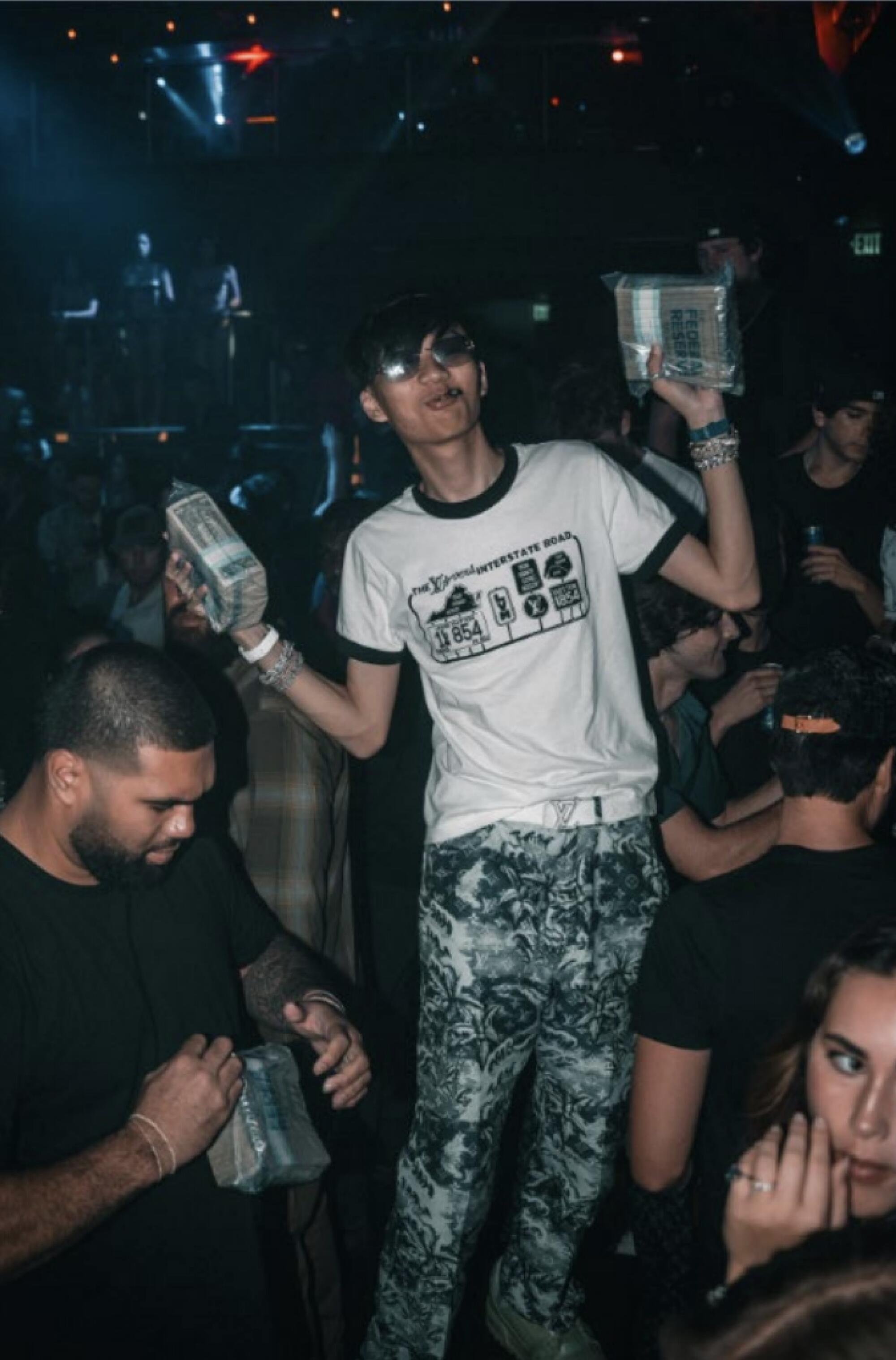A person holds up two bricks of money notes.