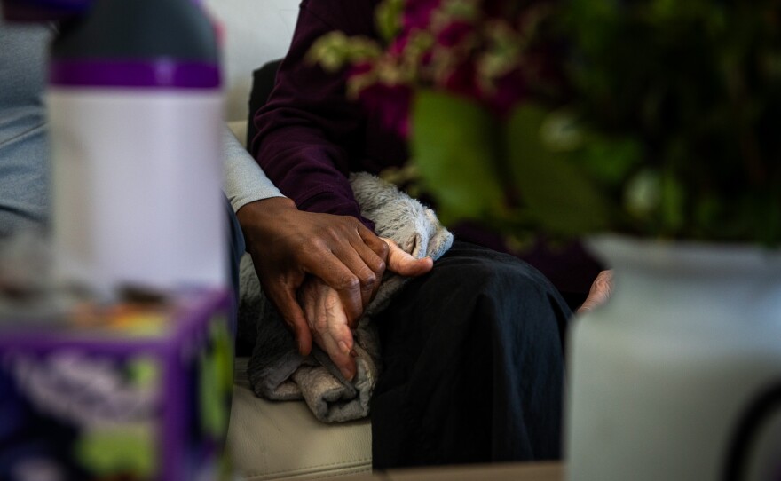 Dr. Douglas Moore holds Theresa Margaret Mary Kelly's hand during her final hours on the day she died, February 20, 2026. Moore runs Autonomy Health and helped Kelly with the medical aid and dying process.