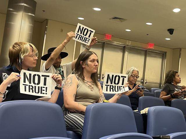 Members of the advocacy group Fresnans for a People’s Budget hold up signs that say “Not True!” at Fresno police departments first ever public engagement meeting on its annual military equipment use report.