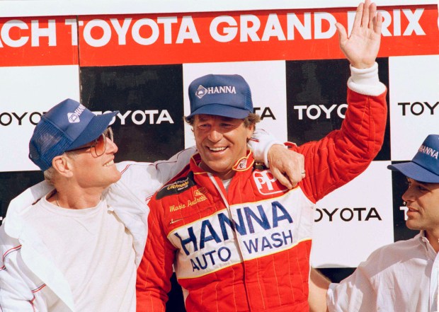Mario Andretti, winner of the 1987 Toyota Grand Prix of Long Beach waves to the crowds and gets a congratulatory hug from friend and team co-owner Paul Newman in the victory circle following the race at Long Beach, Calif., April 5, 1987. (AP Photo/Bob Galbraith)