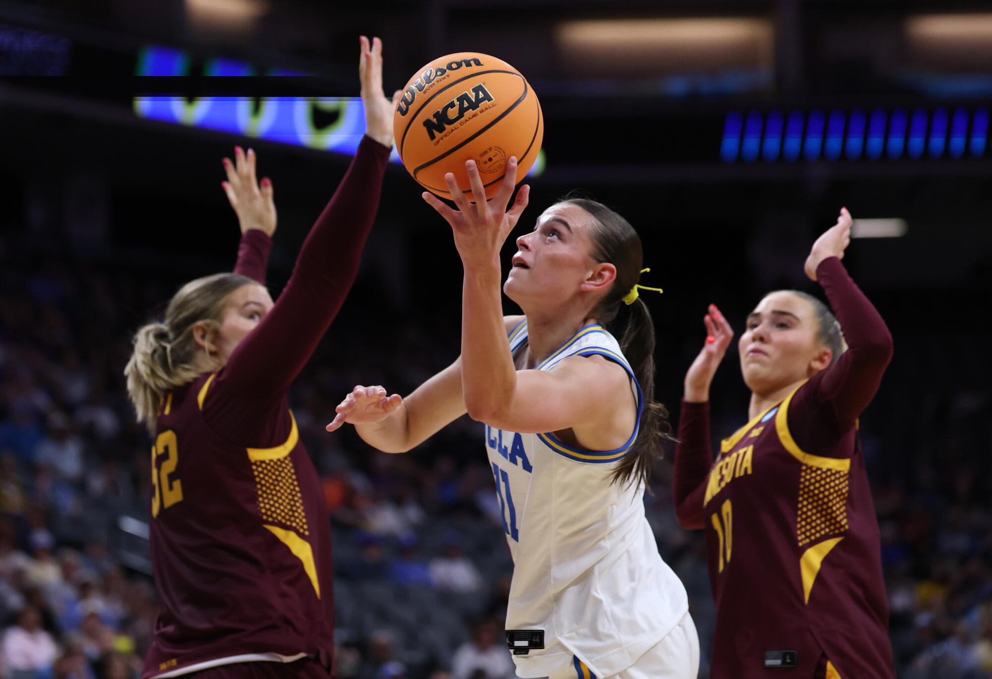 UCLA's Gabriela Jaquez shoots between Minnestoa defenders Sophie Hart, left, and Mara Braun in the first half Friday.