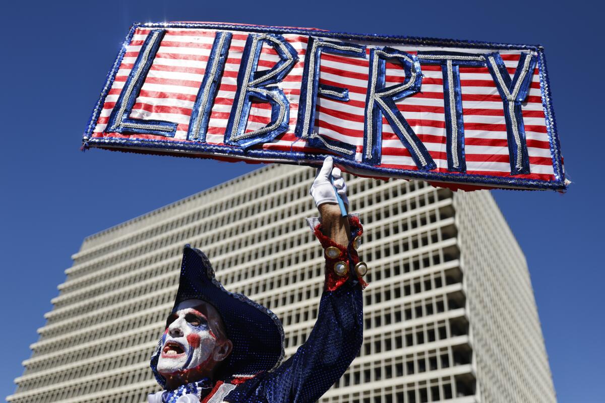 Dandidi, referring to himself as the "harlequin of liberty," holds up a "Liberty" sign at the "No Kings Day" protest.