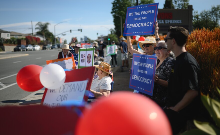 Demonstrators gather at the corner of La Mesa Boulevard and University Avenue in La Mesa, California ahead of a nationwide day of “No Kings” protests against the Trump administration’s sweeping immigration crackdown, military strikes in Iran and other policies on March 28, 2026.