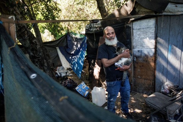 Martin Rodriguez, a long time resident of "The Jungle," with his cat, in front of his makeshift structure in the homeless encampment on March 18, 2026, in San Jose, Calif. (Dai Sugano/Bay Area News Group)