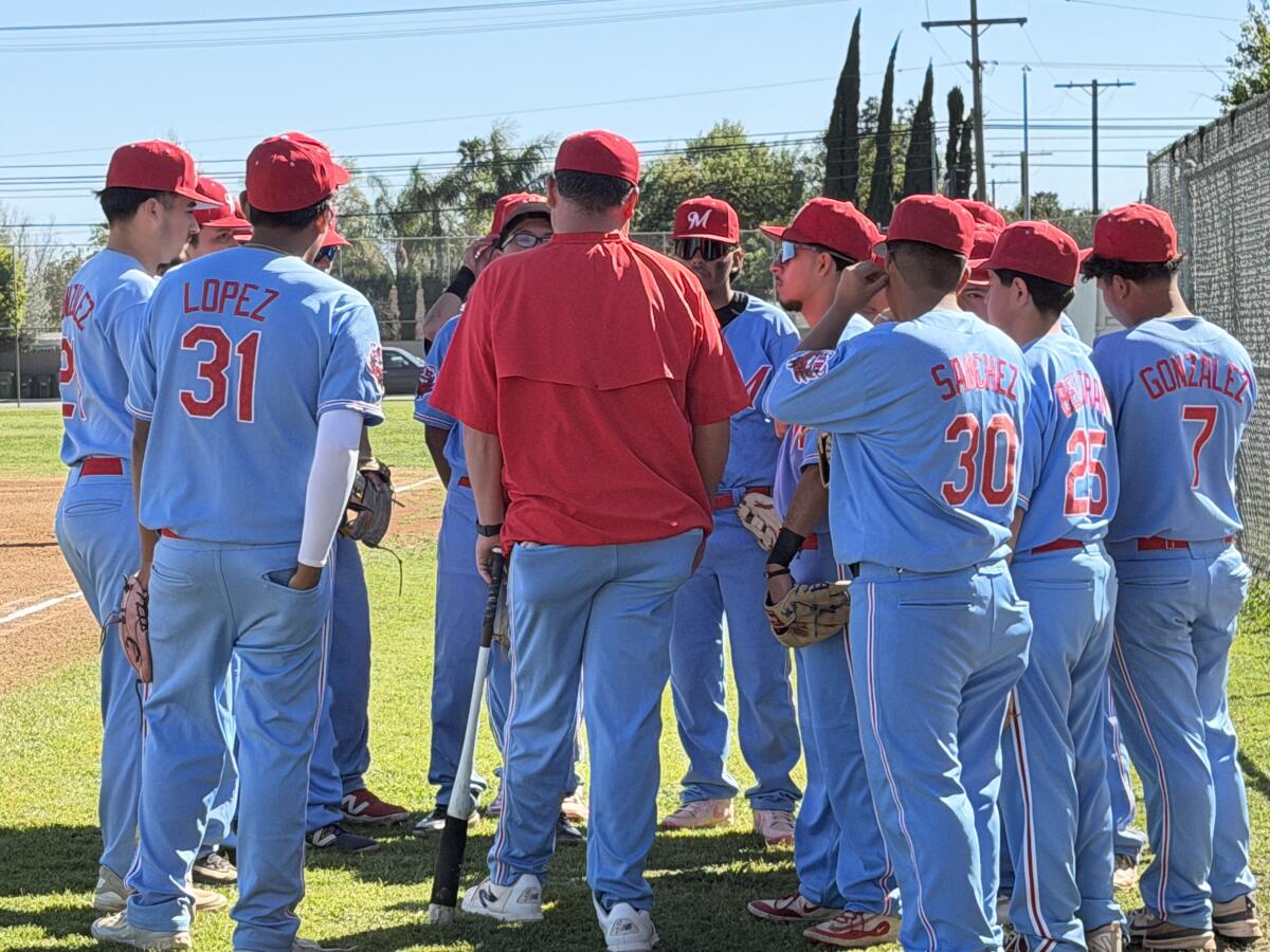 Monroe High baseball players huddle around coach Eddie Alcantar.
