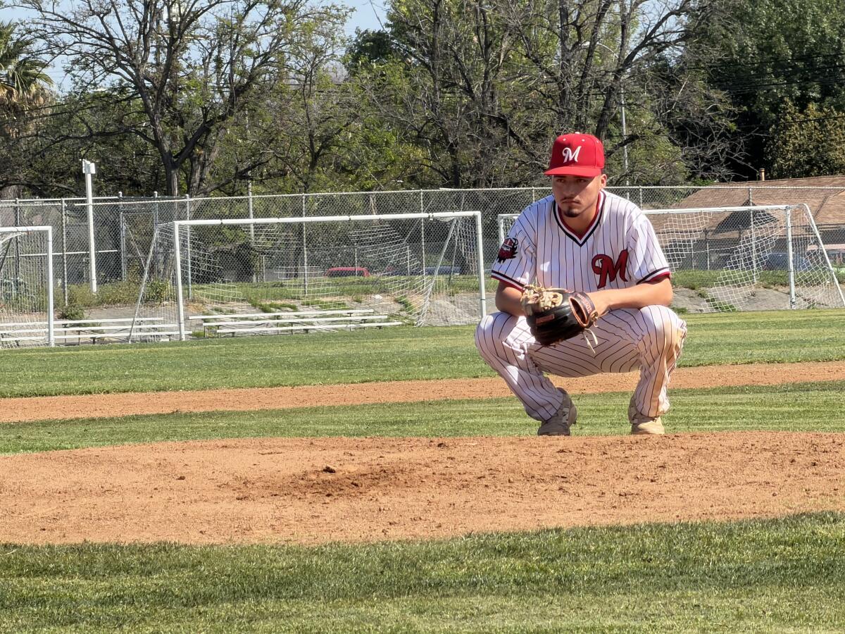 Pitcher Miguel Gonzalez of Monroe High bends down behind the mound.