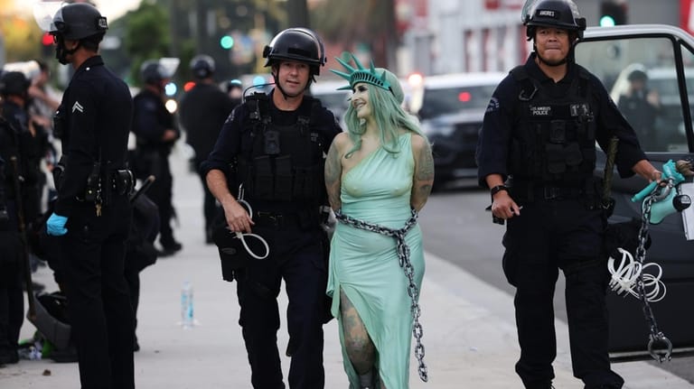 Police arrest a protestor dressed as the Statue of Liberty,...