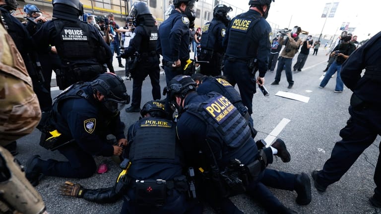 Police detain a protestor near the Metropolitan Detention Center in...