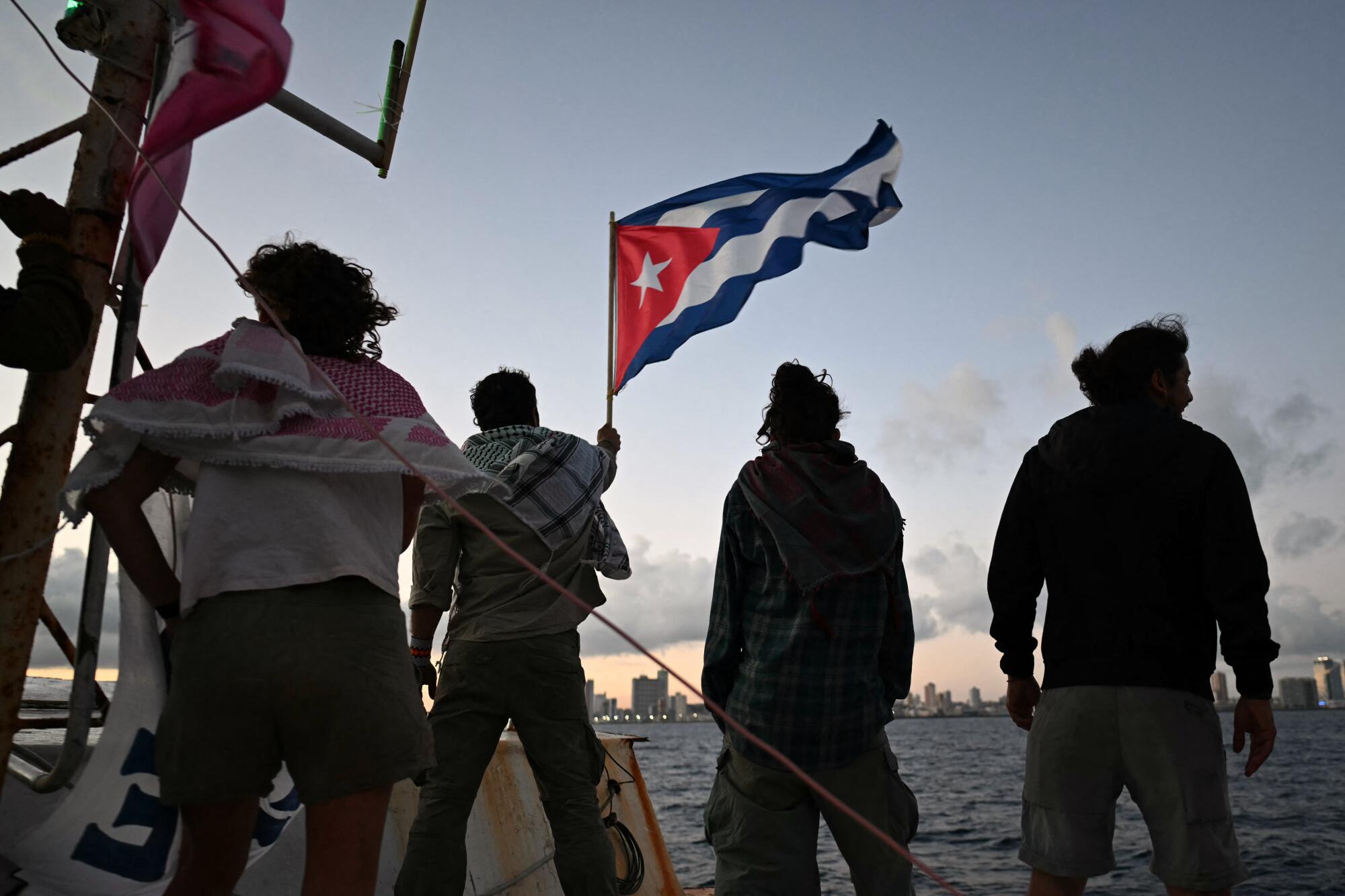 A man waves a Cuban flag on a boat.