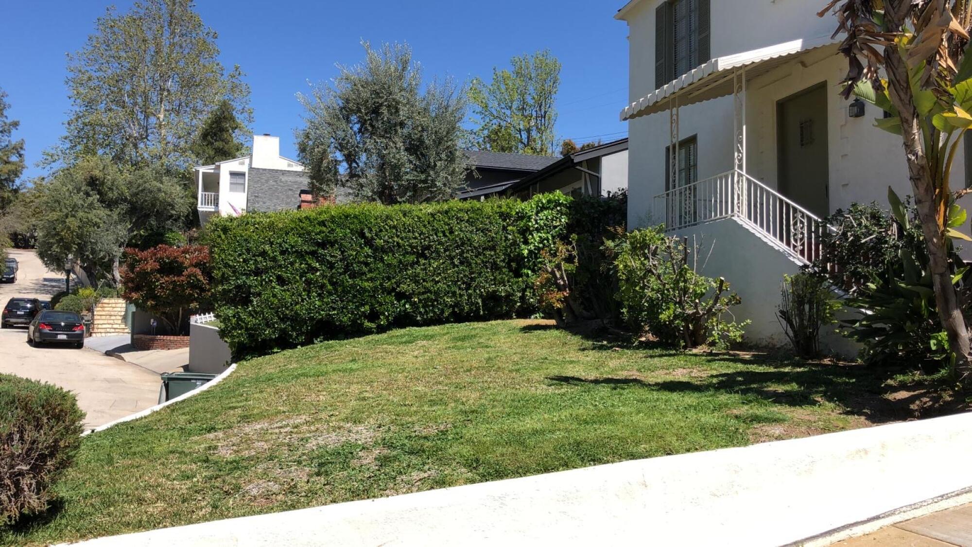 A green lawn and hedge in front of a house.