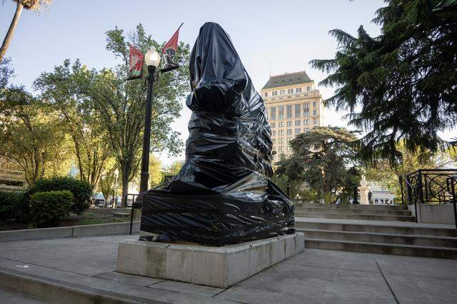 Black plastic covers the statue depicting Cesar Chavez in Cesar E. Chavez Plaza in Sacramento on Friday, March 20, 2026. City officials have announced plans to rename the park after accusations of rape and sexual assault by the civil rights leader surfaced a few days earlier.