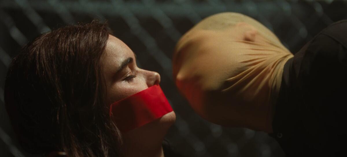 A woman who is bound and gagged is threatened by a captor.