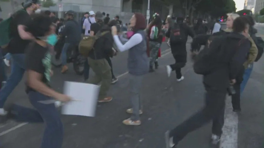 Officers detain protesters as mounted police and tactical units respond to clashes during the “No Kings” protest in downtown Los Angeles.