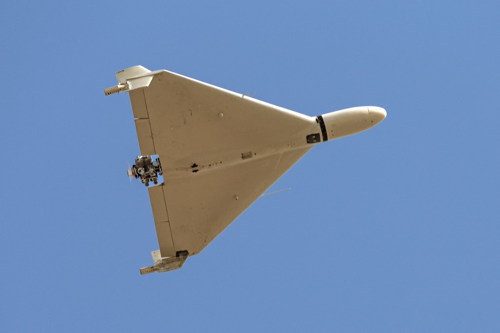 Iranian-made Shahed-136 "Kamikaze" drone flying against a clear blue sky.