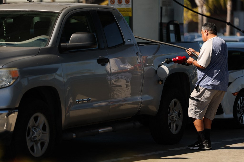 A man refuels his truck at a gas station.