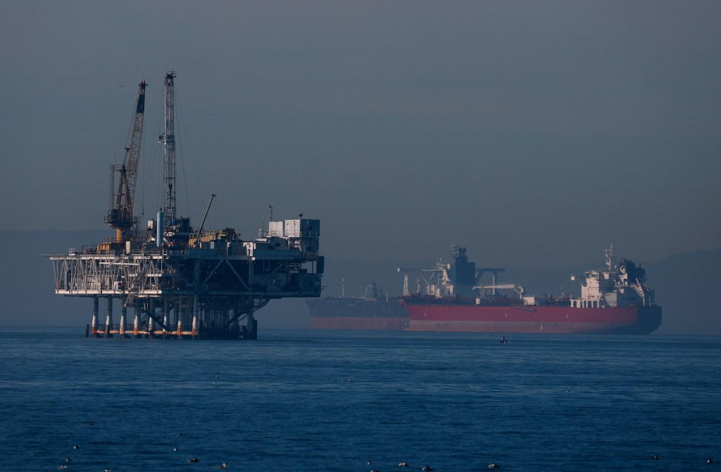 Offshore oil rig Esther in Seal Beach, California with a red tanker ship in the background.