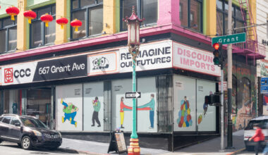 corner building with illustrations in windows, red lanterns hanging across street