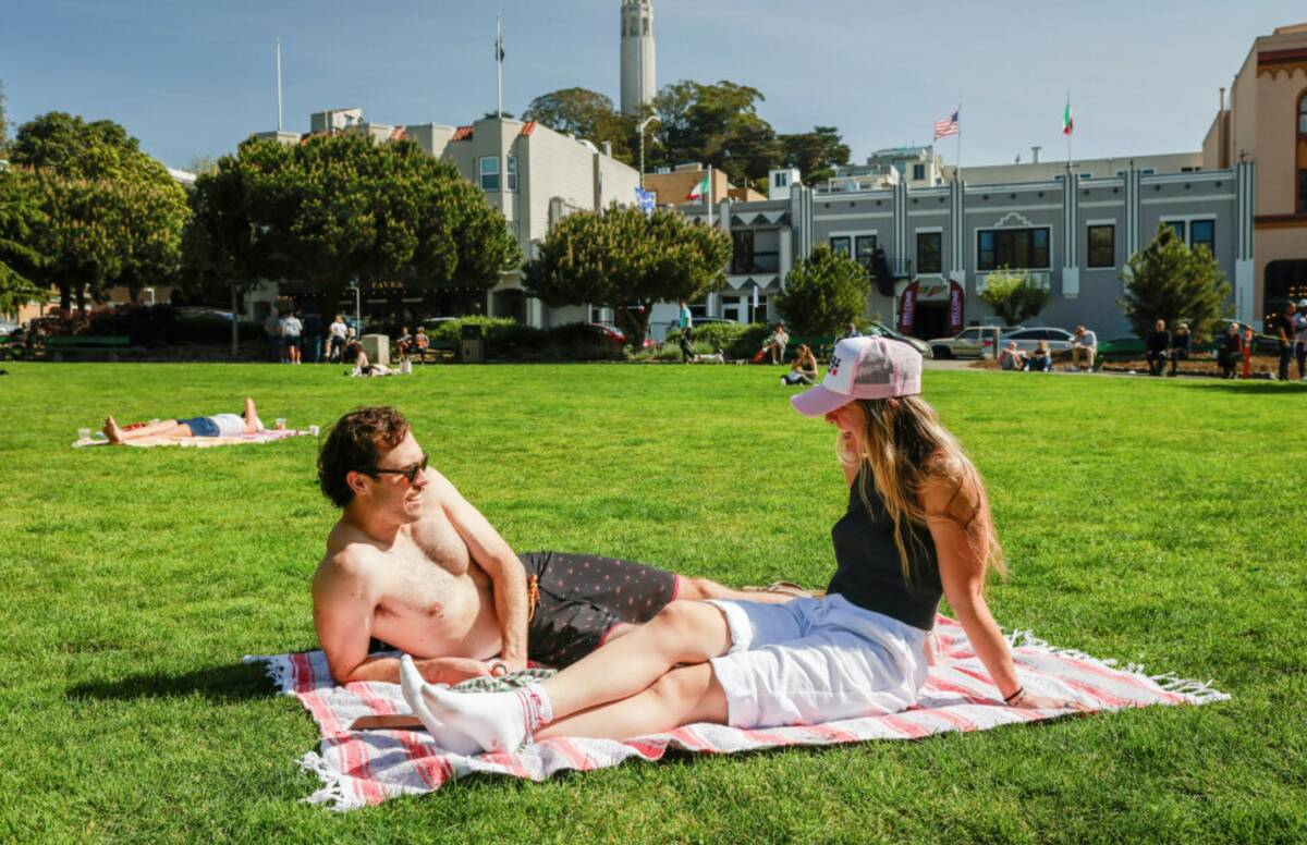 Nick Gardetto, left, and Madi Hirsch lounge in the sun at Washington Square during a heat wave ...