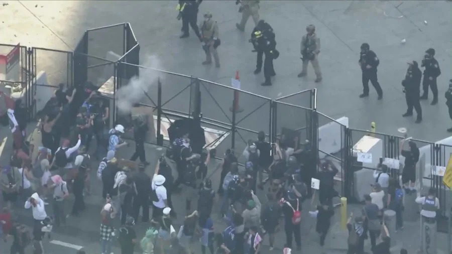Officers detain protesters as mounted police and tactical units respond to clashes during the “No Kings” protest in downtown Los Angeles.