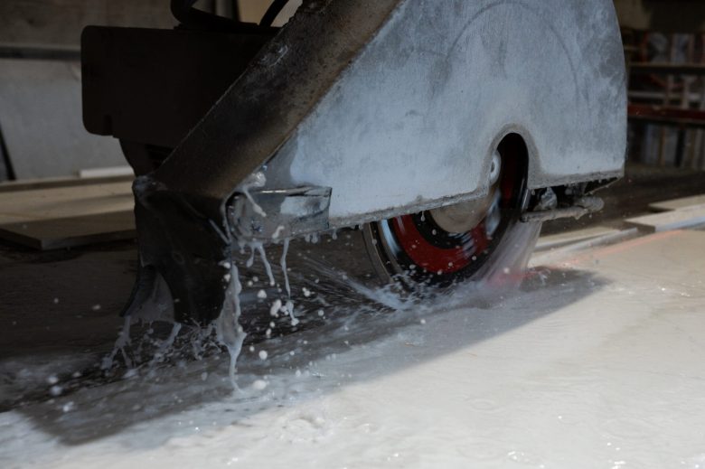 Close-up of an industrial saw cutting stone with water spraying.