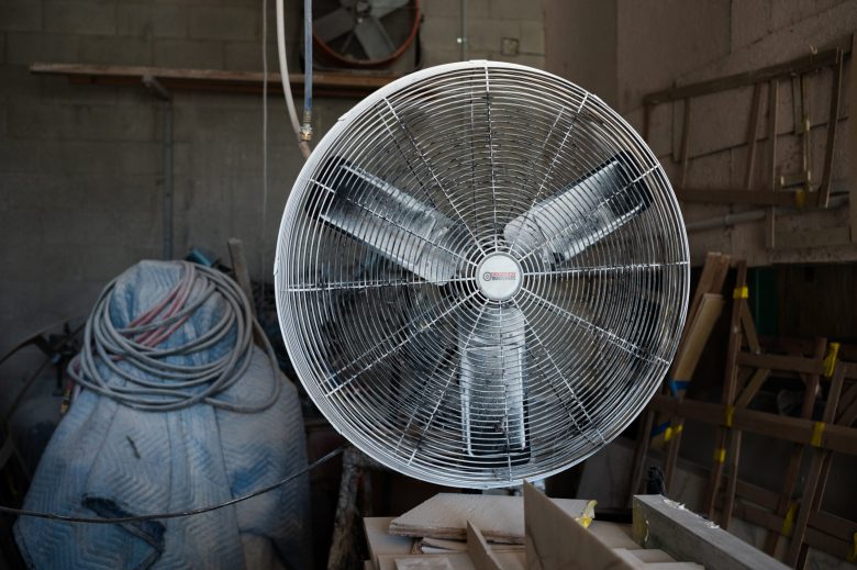 Large industrial fan in a workshop with coiled hoses and wooden structures in the background.