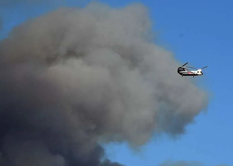 A fire helicopter flies near a large amount of smoke from a California fire last year. The state has been stocking up on fire equipment, but with the unseasonably dry, hot weather this March, officials are worried about the 2026 fire season. Gene Blevins/ZUMA Press Wire/dpa