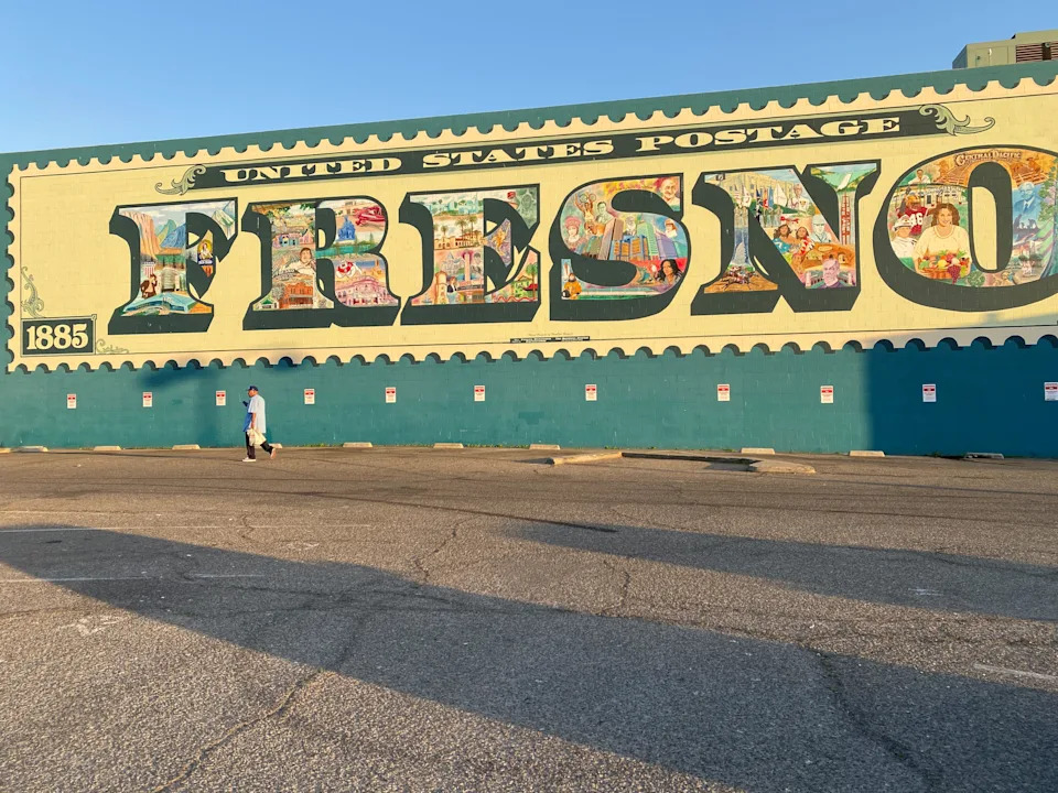 A pedestrian walks by a mural depicting the history, culture and economy of the California Central Valley city of Fresno;