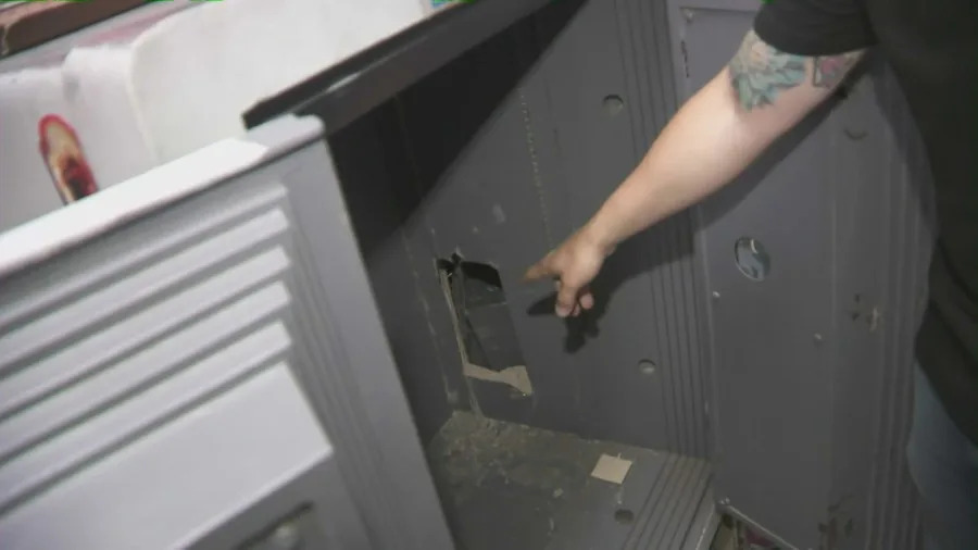 Jonathan Youssef points to a hole that was drilled by thieves who ransacked his jewelry store in Simi Valley on May 25, 2025.