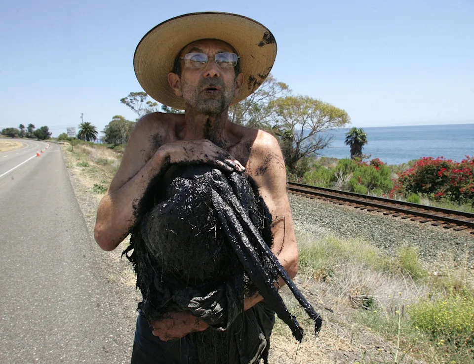 Reeve Woolpert holds an oil-covered pelican he rescued from an oil sludge in the ocean near Refugio State Beach on May 20, 2015.