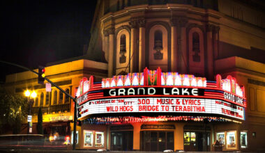 A large building at night with a light-up marquee advertising the movies 300, Music and Kyricws, Wild Hogs and Bridge to Terabithia.