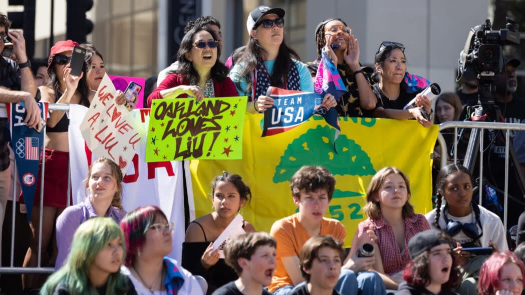 Attendees hold signs during a rally celebrating Olympic gold medalist Alysa Liu’s accomplishments at the Milano Cortina 2026 Olympics on March 12, 2026 in Oakland, California. Liu won the United States first gold medal in women’s singles figure skating since 2002. (Photo by Benjamin Fanjoy/Getty Images)